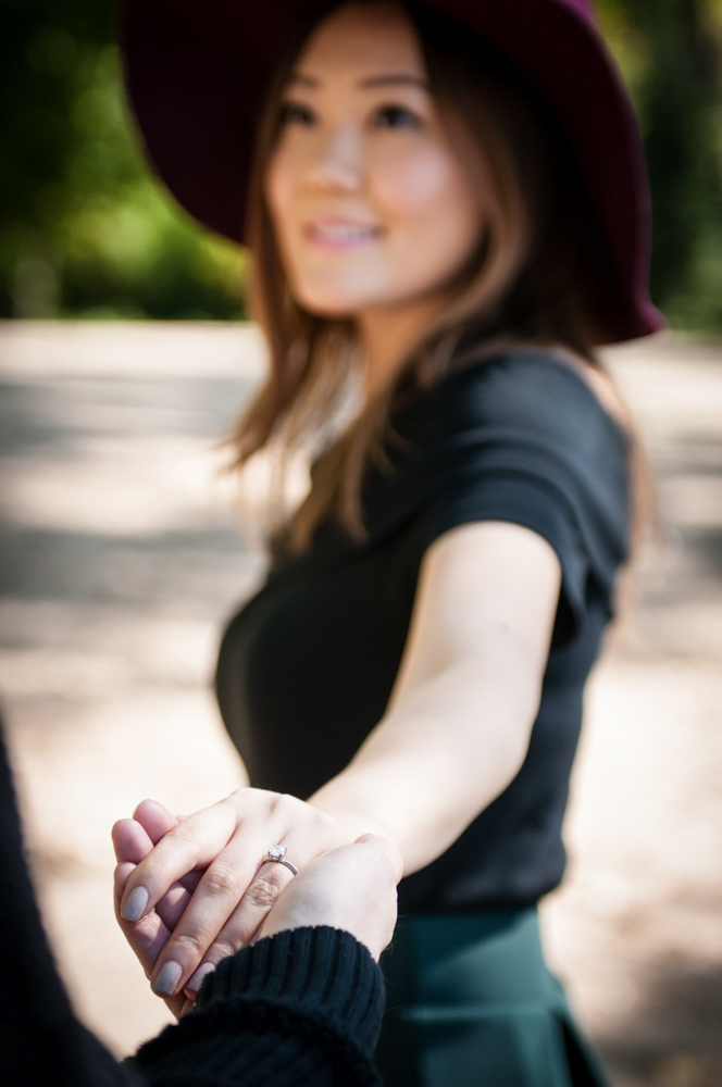 Woman showing engagement ring holding man's hand 