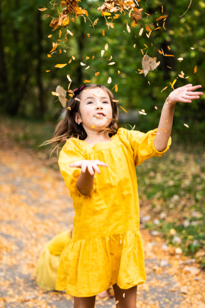 Little girl throwing leaves at Minnehaha Creek in Minneapolis