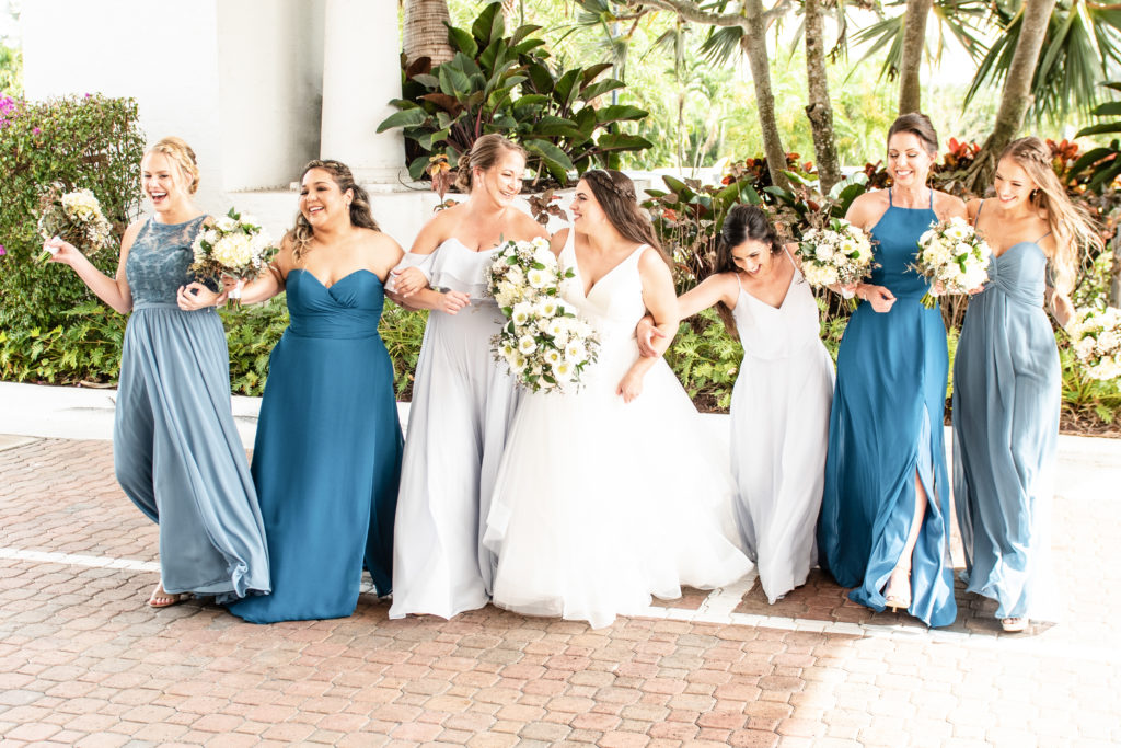 Bridesmaids linking arms with bride
