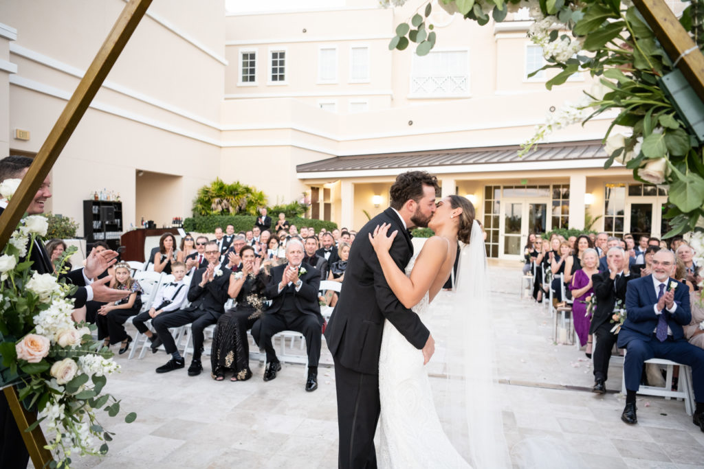 Bride and groom kissing under arch at Wyndham Grand in Jupiter 