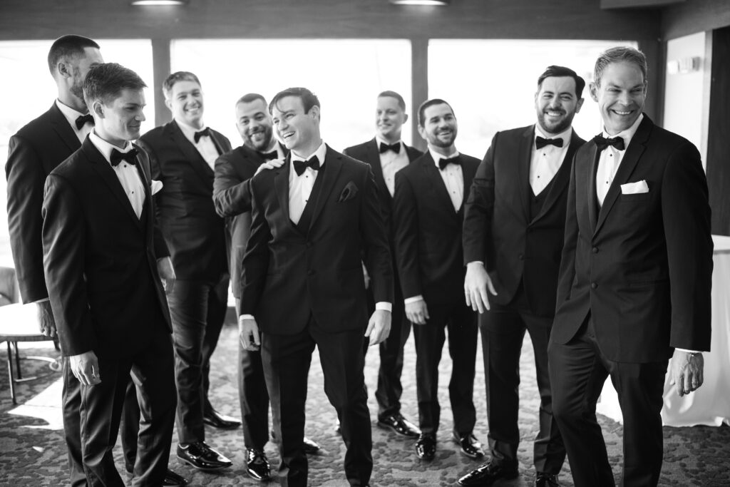 Groomsmen laughing in tuxedos before wedding ceremony 