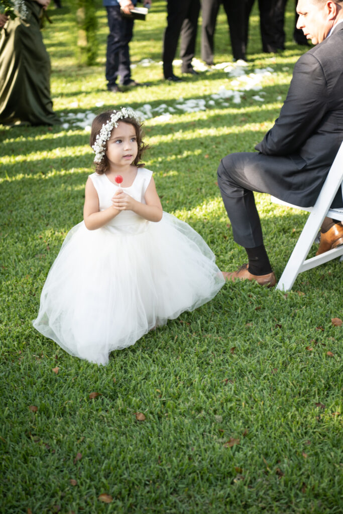 Flower girl holding sucking in dress during wedding ceremony 