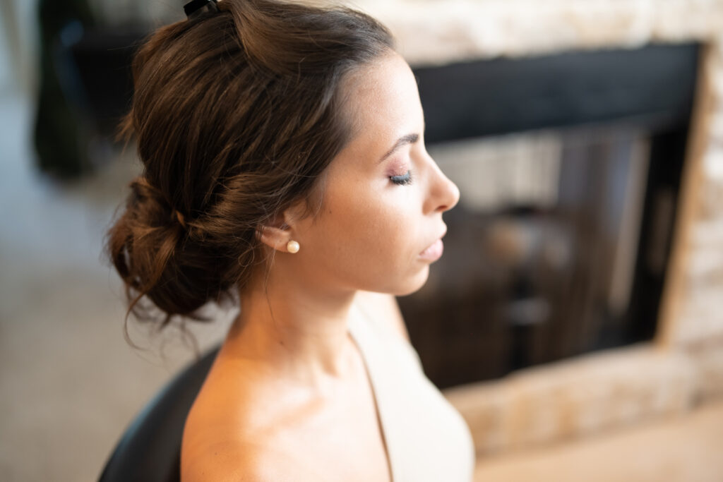 Bride with hair pinned getting makeup done for wedding 