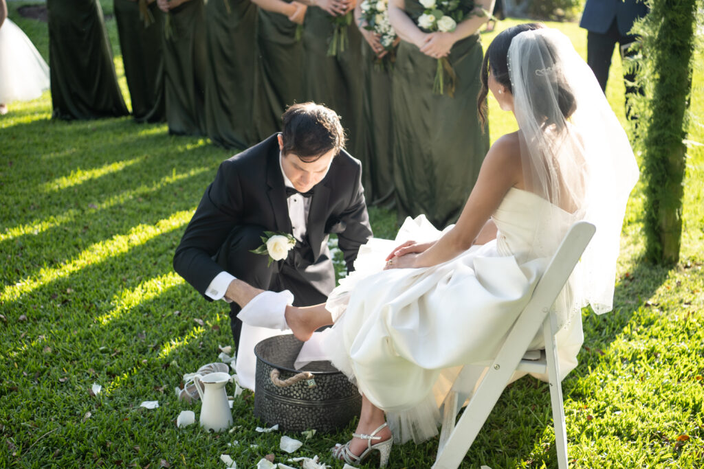 Groom washing bride's feet during wedding ceremony 