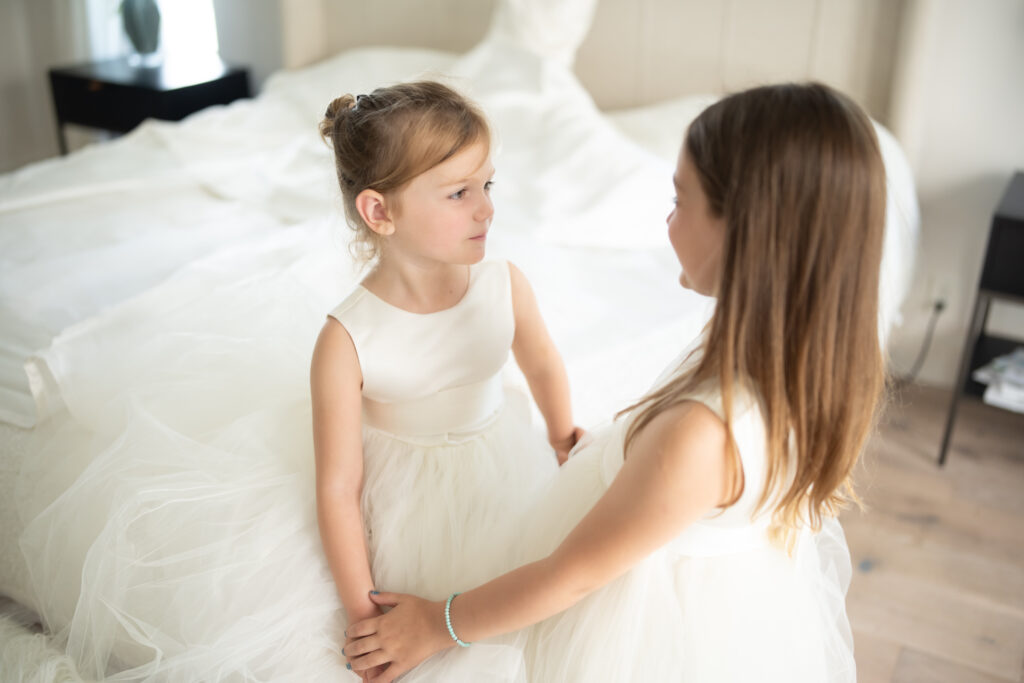 Flower girls admiring each other in dresses on wedding day 